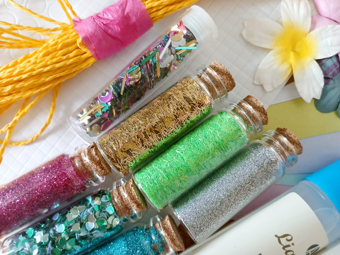 A photo of some different coloured glitters and sequins for cardmaking.