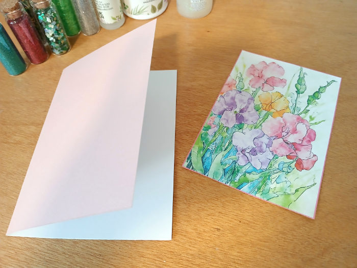 The folded pink card stock next to the flower picture card topper - the summer flower artwork is by creative artist Kay Burton.