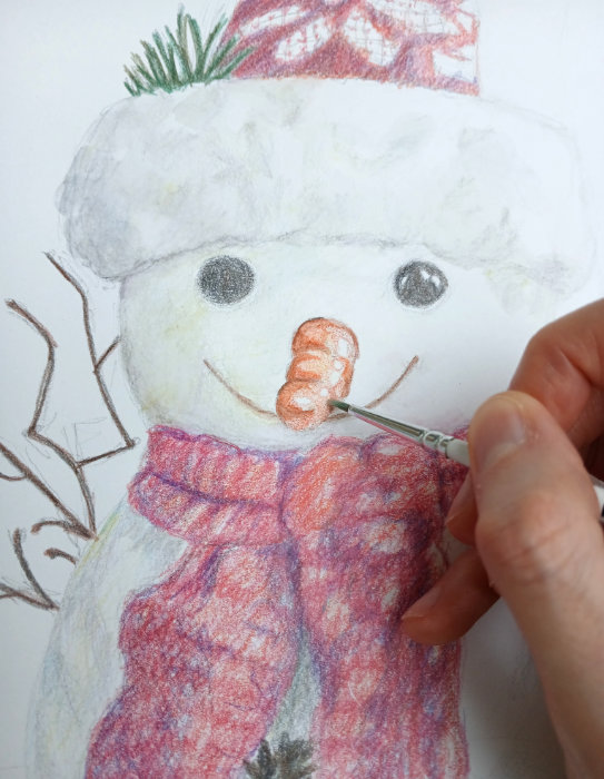 Ruth Burton adding water to the crayon with a paintbrush on her festive artwork.