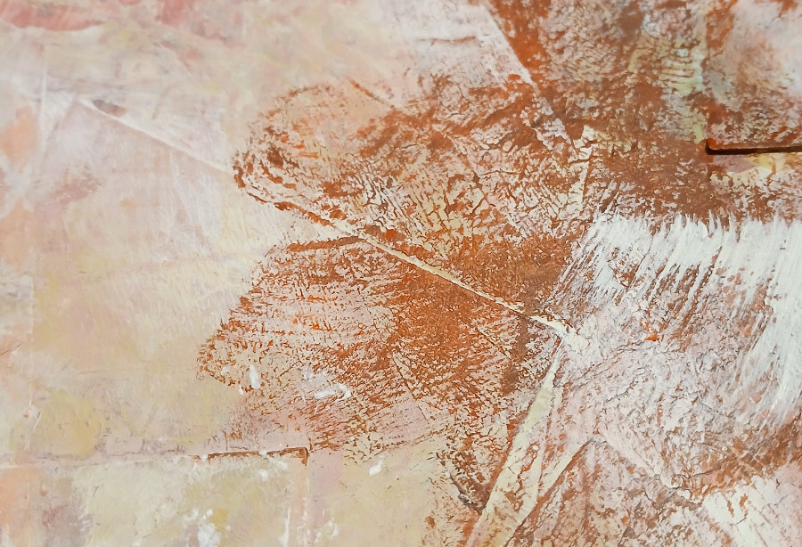 A close up of an abstract stamped pattern using orange-brown acrylic paint.