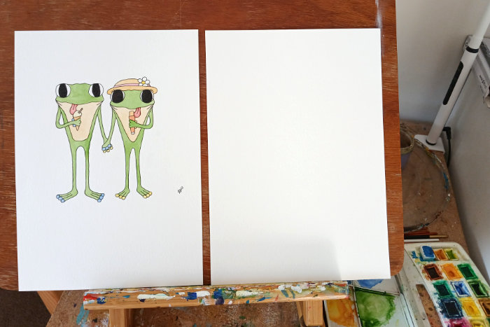 A photo of the original Frog's Bucket List painting called 'Ice Cream' next to a blank piece of watercolour paper - the original is of frogs eating ice cream.