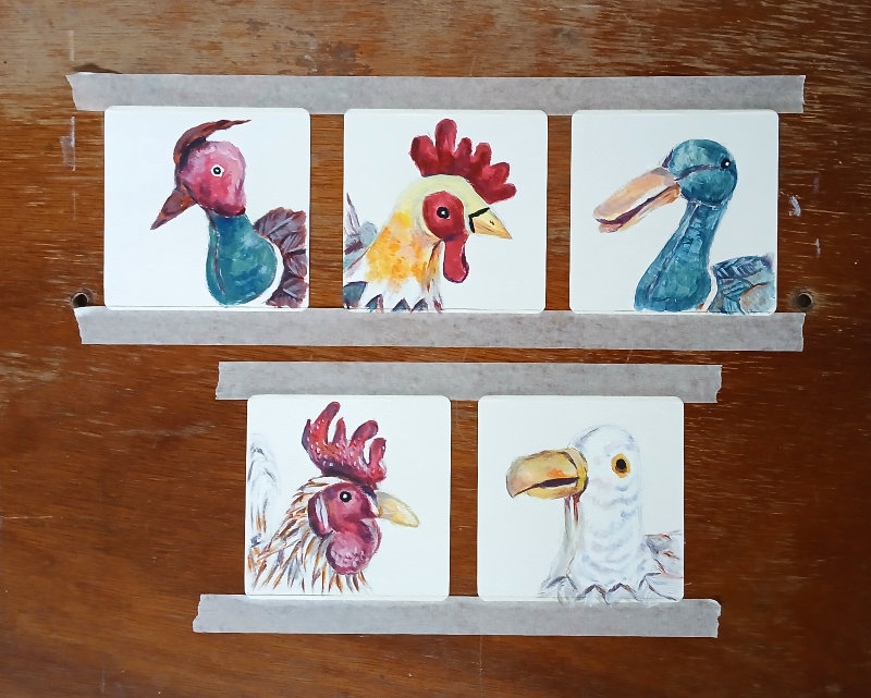 The finished bird portrait paintings still on the wooden art board.